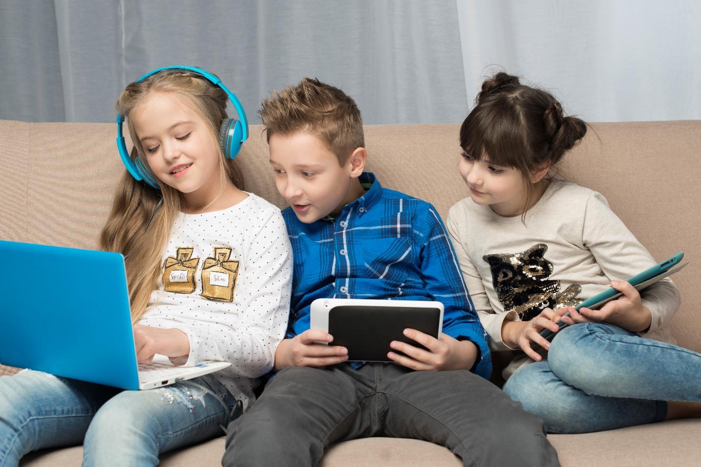 Trei copii utilizand device-uri electroice.